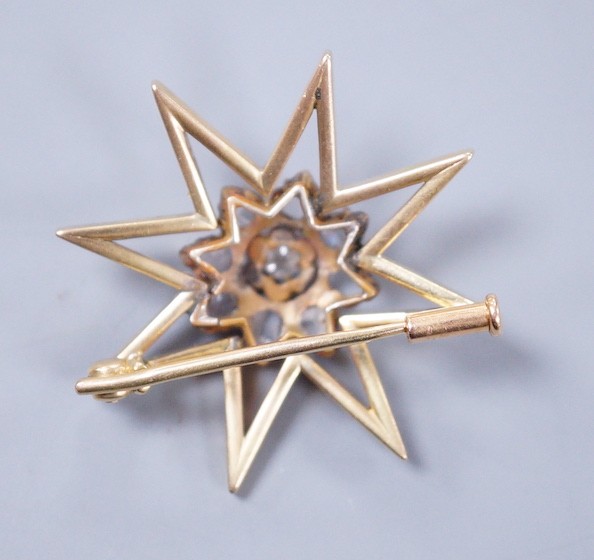 A yellow metal and diamond cluster set star brooch, 30mm, gross weight 6.6 grams.